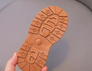 Close-up van bruine rubberen zool met antislip profiel en maat 23 voor kinderlaarzen