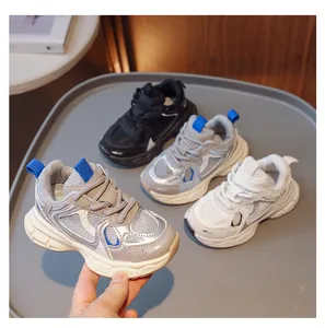 Three colors of breathable mesh kids sneakers on a tray with one held by a hand