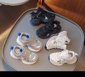 Three pairs of breathable mesh kids sneakers in black silver and white on a tray