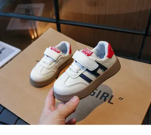 Détail de baskets enfant en cuir blanc avec rayures bleues et fermeture à bande velcro