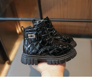Macro detail of black patent leather kids boots with quilted texture and rhinestone buckle