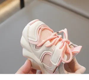 Close-up of pink and white kids' mesh sneakers featuring breathable fabric and thick sole