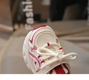 Gros plan sur la maille respirante et les coutures rouges des baskets blanches enfant