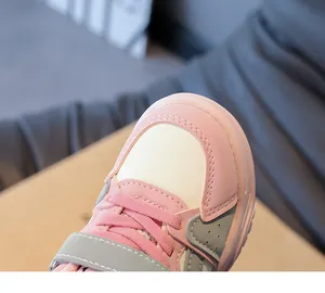 Detailopname van roze en beige kindersneakers met klittenbandsluiting en stevige stiksels