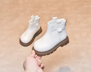 Close-up of white leather kids Chelsea boot with thick non-slip brown sole and cross-stitching