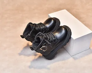 Detail of black leather kids boots with side zipper and decorative metal buckle strap