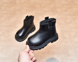 Detailed close-up of kids black leather boots showing durable rubber soles and stitching