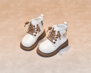 Detail of white leather kids martin boots with brown laces and side zipper closure