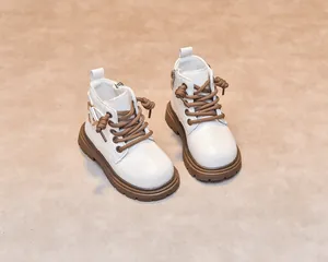 Detailed front view of white leather kids boots with brown laces and rubber soles