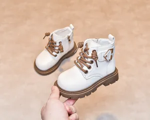 Detail view of white kids' boots showing the side zipper and brown non-slip rubber sole