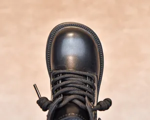 Close-up of black kids' Martin boots showing lychee texture leather and durable stitching