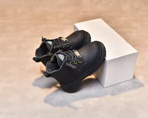 Détail de bottines noires pour enfants avec texture cuir, zip latéral et lacets