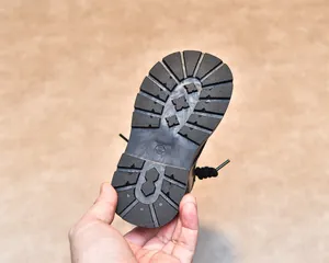 Detailed view of children's boots featuring a non-slip black rubber sole with deep tread