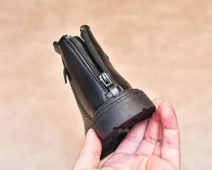 Close-up of the rear metal zipper and thick non-slip rubber sole on black boots