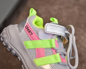 Gros plan de baskets en mesh gris respirant avec détails roses et semelle pneu