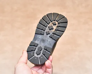 Detail of black non-slip rubber sole with deep grooves and size marking on kids boots