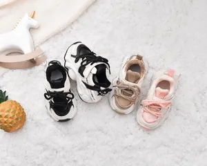 Detail of plush winter baby sneakers on soft white rug with colorful patchwork design