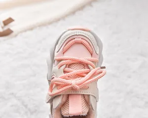 Close-up of pink and beige kids winter sneakers with warm fleece lining and mesh texture
