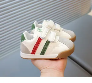 Detail of kids white sneakers with red green stripes and dual hook and loop straps