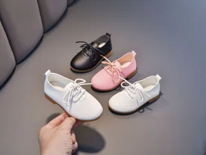 Close-up of kids leather shoes in white, pink and black with litchi grain texture