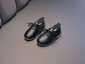Detail of black pebbled leather oxford shoes for children with durable brown rubber soles