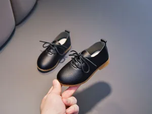 Close-up of black leather children's shoes with brown rubber sole and lace-up detail