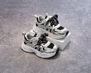 Détail de baskets enfant en maille argentée avec rayures noires et semelles blanches