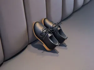 Detailed macro view of black lychee grain leather kids shoes with classic lace-up design