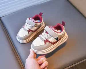 Detail of burgundy and beige kids sneakers with velcro straps and 1987 embroidery