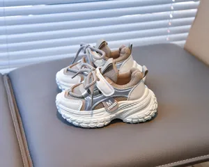 Détail de baskets enfant avec patchwork argenté et bande velcro sur une chaise grise