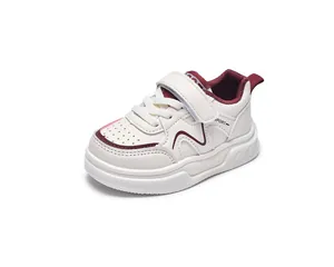 Close-up of beige leather kids sneakers with red trim, velcro strap and sport details