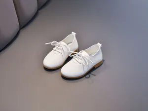Detailed view of white children's oxfords with litchi texture and brown rubber sole