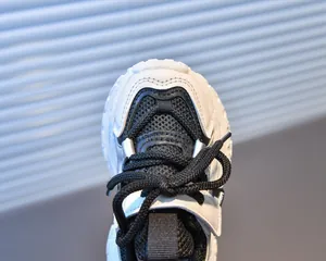 Détails de chaussures de sport pour enfants montrant le mesh noir et empiècements blancs