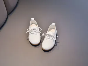 Detail of white leather kids shoes with lychee texture and brown rubber soles