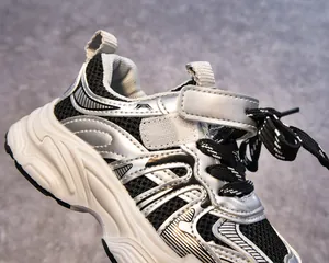 Gros plan de chaussures de sport enfant en mesh respirant avec détails argentés et velcro