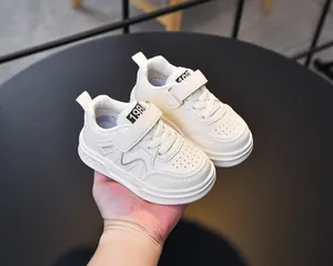 Detail of white kids sneakers with hook-and-loop straps and 1987 sport lettering