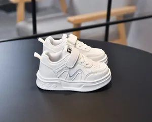 Detail of white leather kids sneakers featuring velcro straps and embossed sole patterns