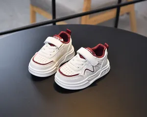 Detailed macro view of white and burgundy kids leather sneakers with velcro closure
