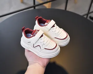Detail of kids leather sneakers with velcro straps and non-slip soles in beige and red