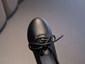 Detail shot of black leather girl's shoe with textured finish and decorative bow tie knot