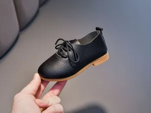 Close-up of children's black leather lace-up shoes with lychee texture and rubber soles