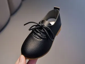 Detail of black leather kids' Oxford shoes showing litchi texture and lace-up closure