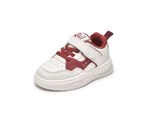 Détail de baskets en cuir pour enfants avec velcro et bout perforé respirant en blanc et bordeaux