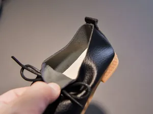 Close-up of black leather kids oxford shoe featuring premium texture and durable rubber sole