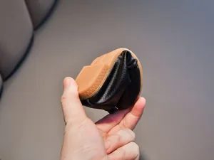 Macro shot of a black leather shoe being folded to show the flexible brown rubber sole