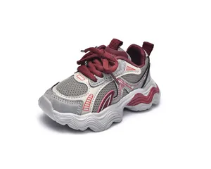 Detail of grey and maroon kids sneakers featuring mesh upper and thick wavy outsole