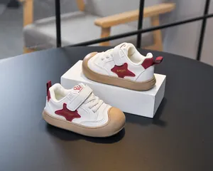 Detail of white kids sneakers with red star patterns, velcro straps and rubber toe caps