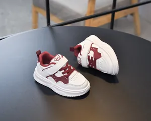 Détail de chaussures de sport enfant en cuir blanc et bordeaux avec velcro et semelle antidérapante