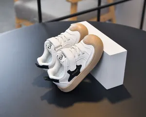 Close-up of kids white sneakers with brown rubber toe cap and Velcro strap for easy wear