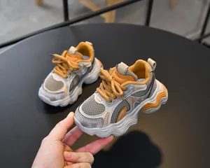 Detailed macro view of the grey mesh and orange leather panels on the girl's sneakers